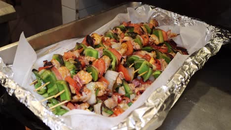 person serving shrimp skewers on a food insert