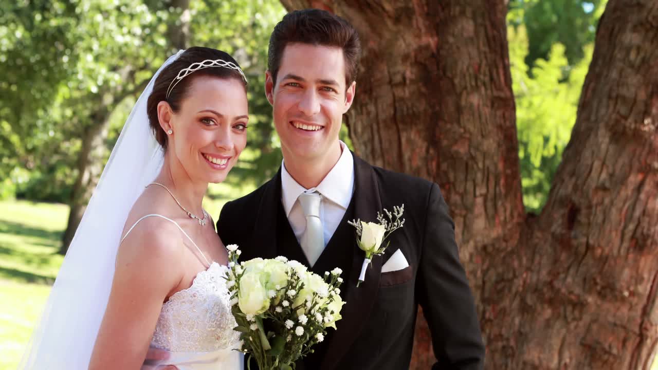 recién casados felices sonriendo a la cámara