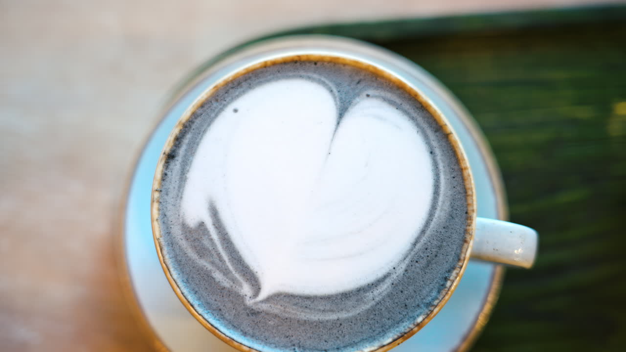 Blue matcha latte with heart shape foam in a ceramic mug