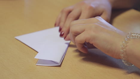 close up of a women's hands folding an origami boat