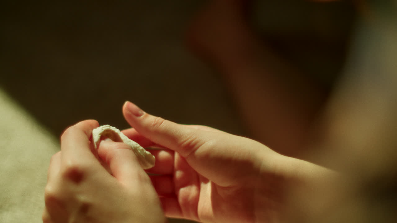 Close up of hands holding a small white object