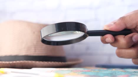 exploring a map with a magnifying glass and a hat