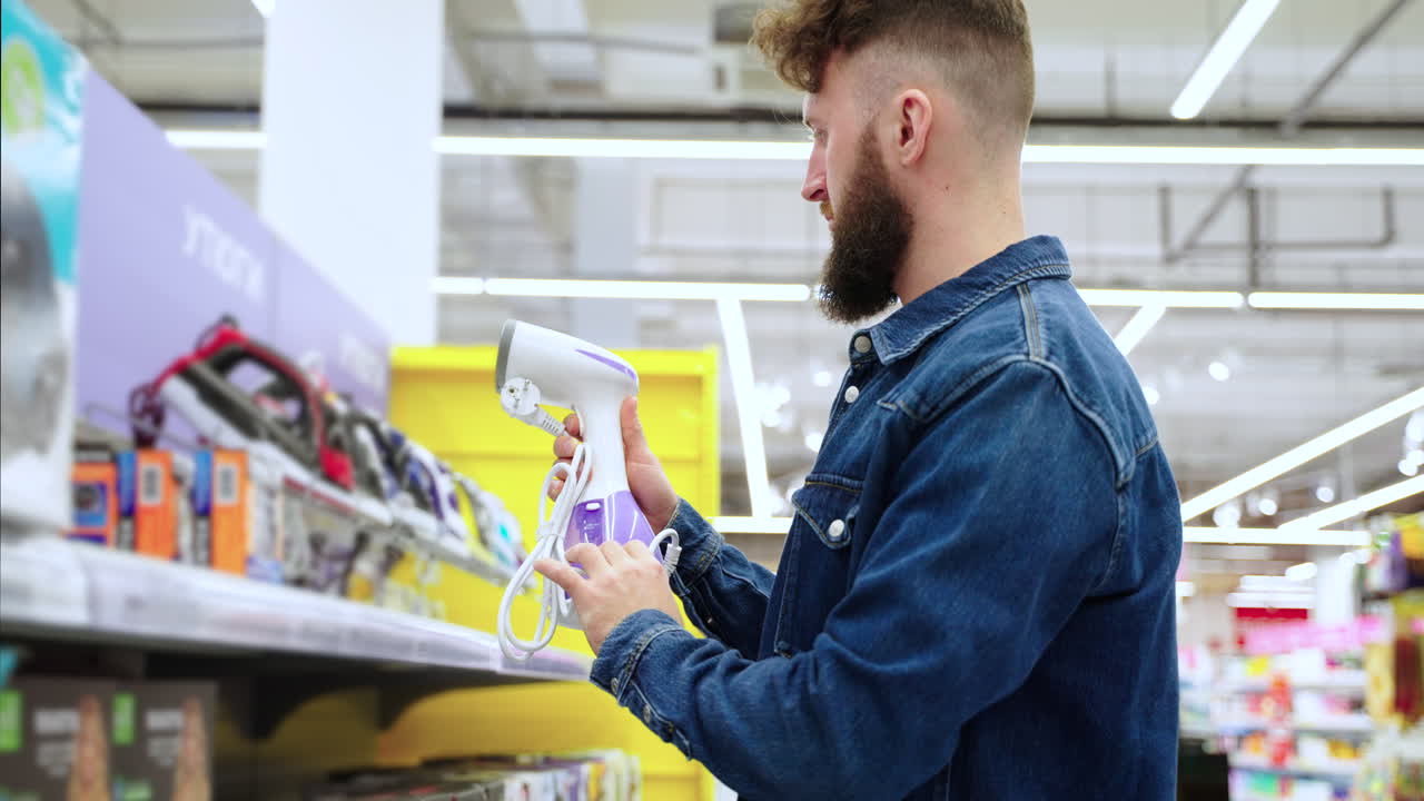 hombre mirando un hierro de vapor de mano en una tienda