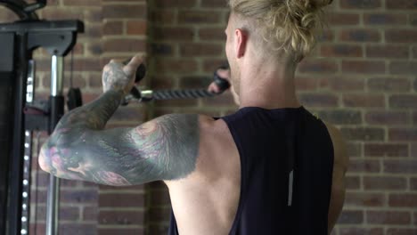 Músculos-De-Hombre-Tatuado-En-El-Gimnasio-En-Casa-Haciendo-Tríceps-De-Cable-Sobre-La-Cabeza-Tira-Tiro-Desde-Atrás