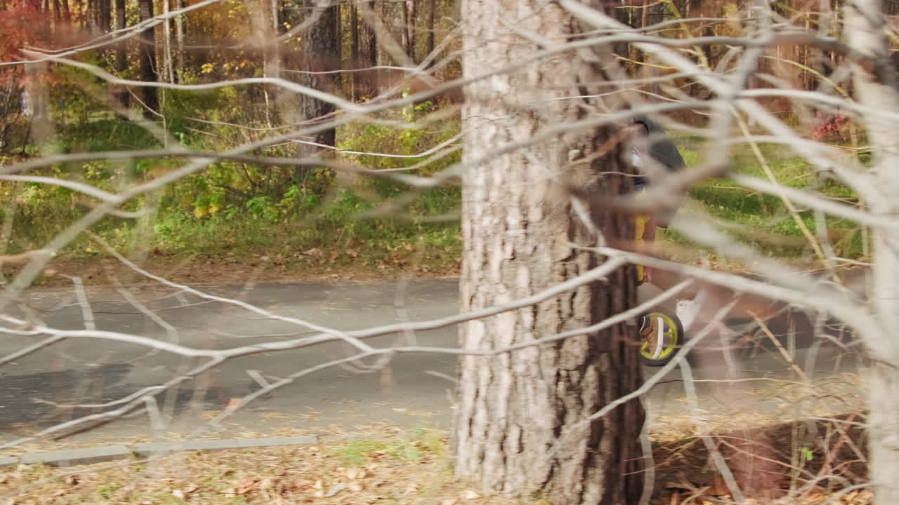 Father helping child ride balance bike in autumn park