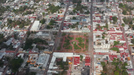 Slide-and-pan-aerial-footage-of-old-cathedral-Iglesia-de-San-Servacio-and-surrounding-town-area.-Valladolid,-Mexico