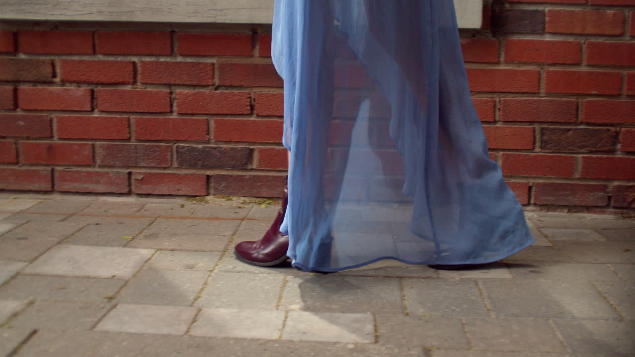 카메라가 오른쪽에서 왼쪽으로 산책하는 것을 추적하는 동안 카우카시안 소녀의 문신 다리가 걸어가고 있습니다.