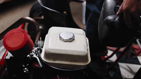 close up shot of mechanic putting the tank cap on his diy go-kart and on the fuel canister he is holding