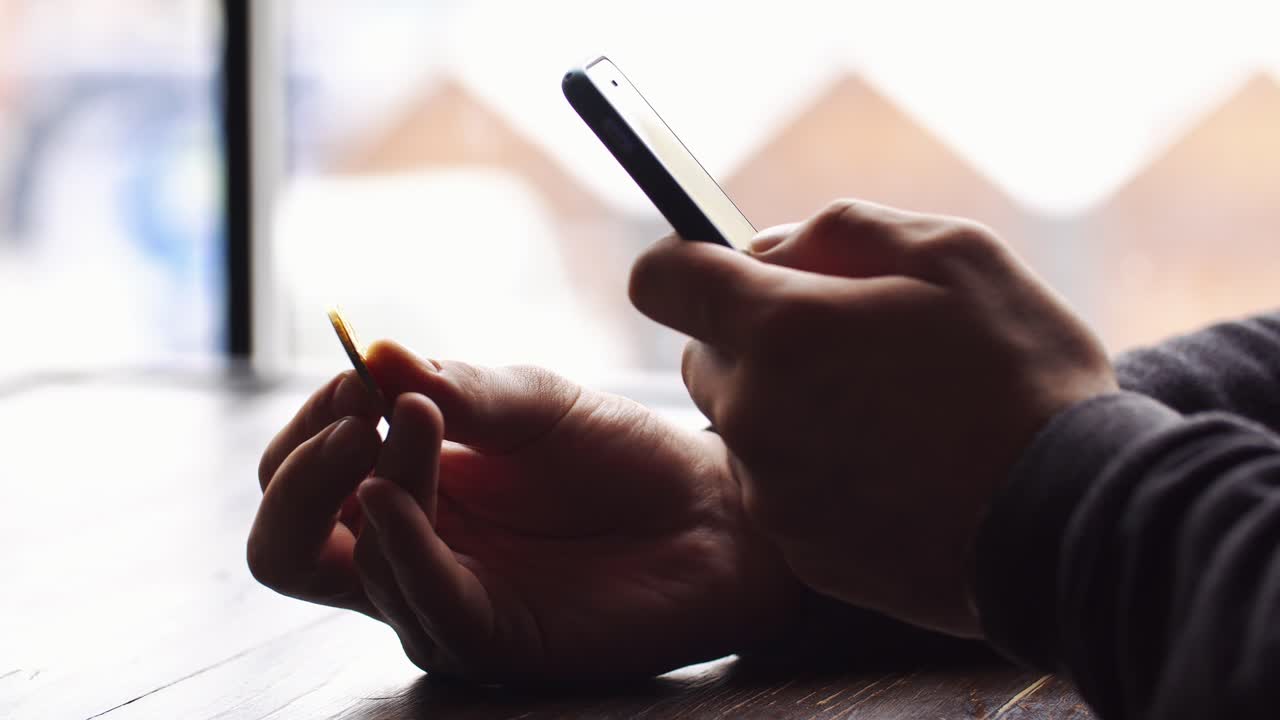 Person holding a coin and smartphone