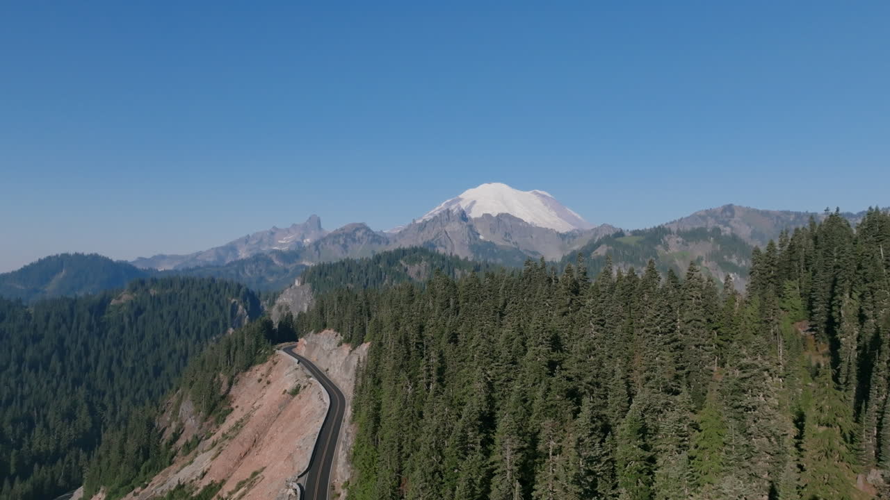 Aerial footage flying over the pine covered hills of Yakima Peak of the Cascade Mountains with Mount Rainier in the background