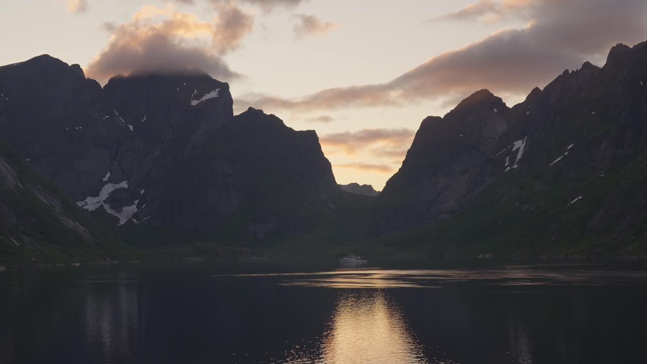 Lofoten sunset over Reine fjord with mountain peaks reflecting in calm water