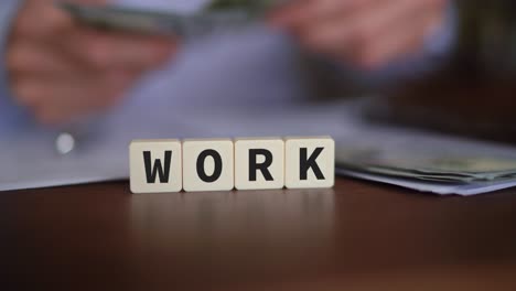 word work in letter blocks with money being counted in blurry background