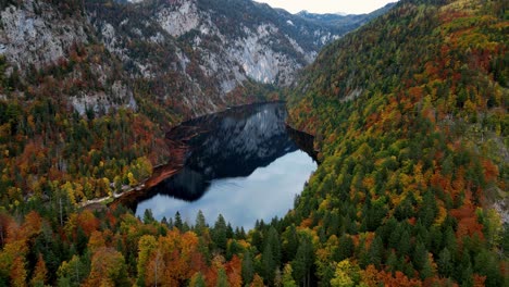 Ein-Ruhiger-Bergsee,-Umgeben-Von-üppigem-Grün-Und-Schneebedeckten-Gipfeln,-Der-Die-Leuchtenden-Farben-Eines-Sonnenaufgangs-Widerspiegelt