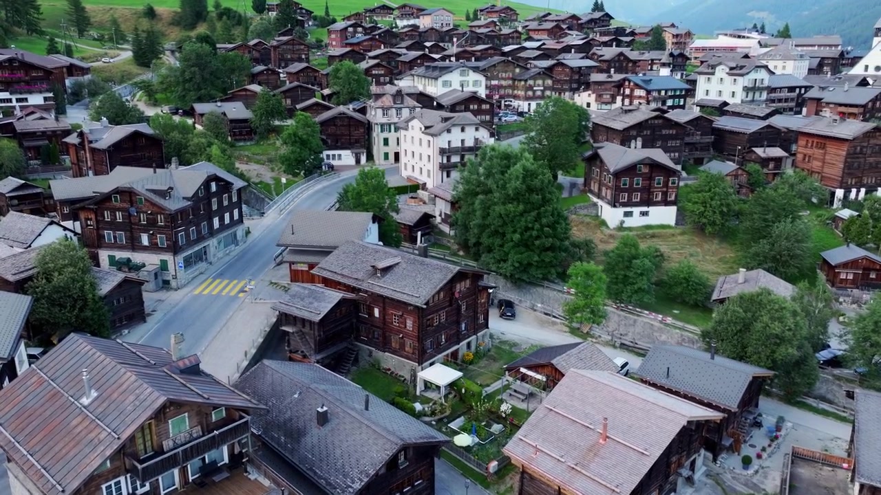 Fredelig luftfoto av Münster landsby med alpine hus, grøntområder og en kirke