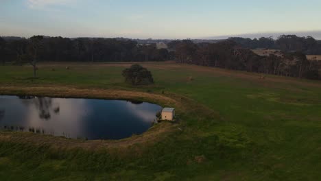 aerial orbit shot over small house and mirror lake during a foggy sunset