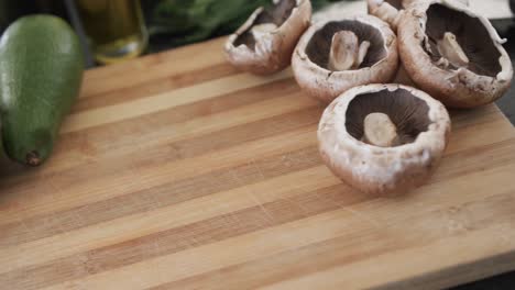 close up of kitchen countertop with wooden chopping board and vegetables, slow motion