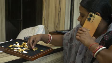 indian woman selling gold jewelry on the phone