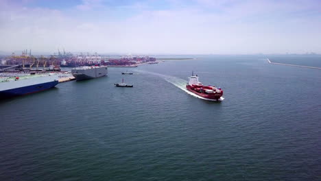 Aerial-view-of-logistics-concept-cargo-ship-sailing-out-to-the-open-sea-leaving-Laem-Chabang-dockyard-in-Chonburi-Province,-Thailand