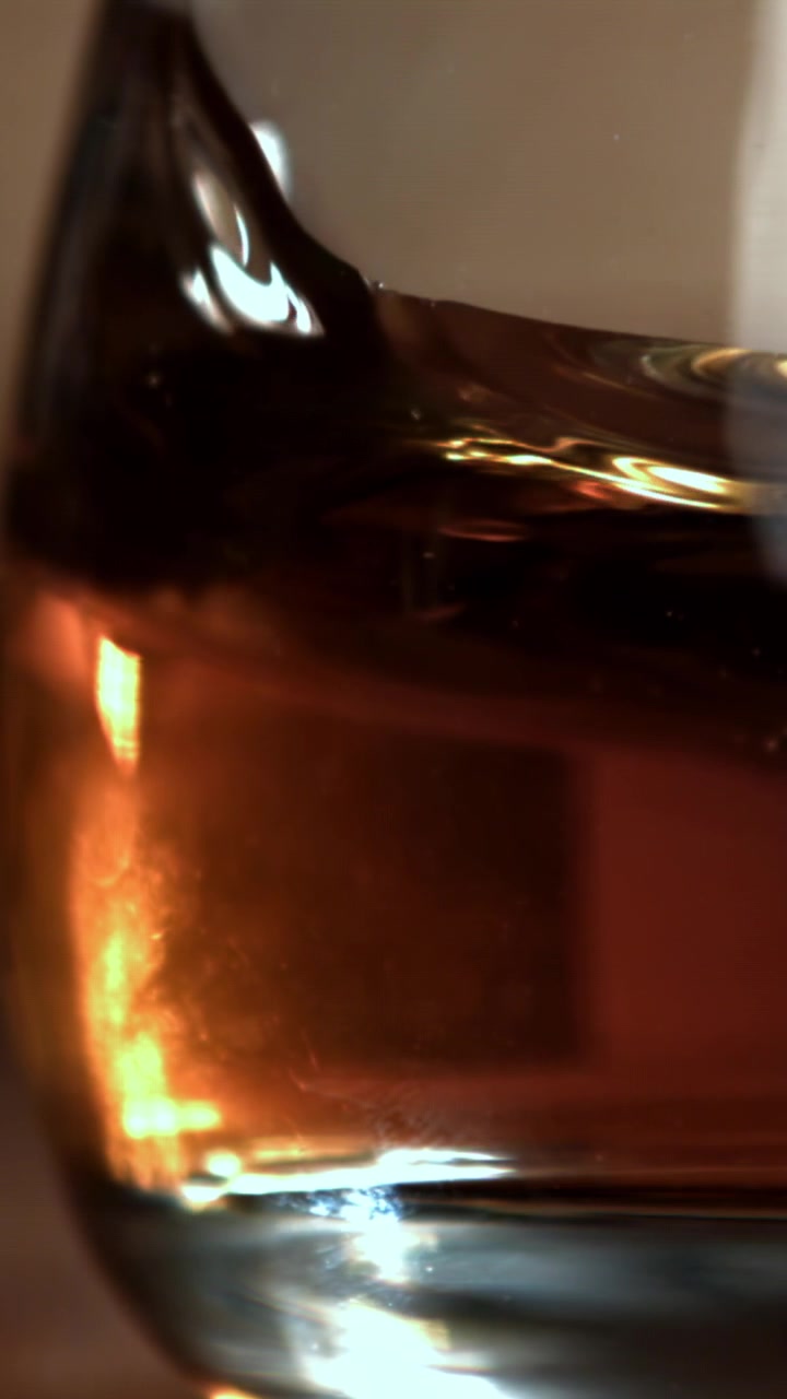 Primo piano di whisky ambrato che vortica in un bicchiere