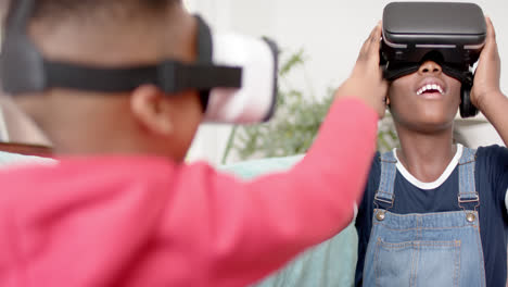 African-american-sister-and-brother-using-vr-headset-in-living-room,-slow-motion