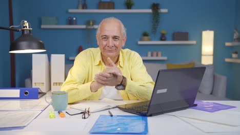 Home-office-worker-old-man-makes-a-trust-sign-to-the-camera.