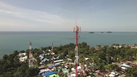 aerial orbit drone shot of telecommunications tower on a tropical island in thailand with jungle and islands and ocean