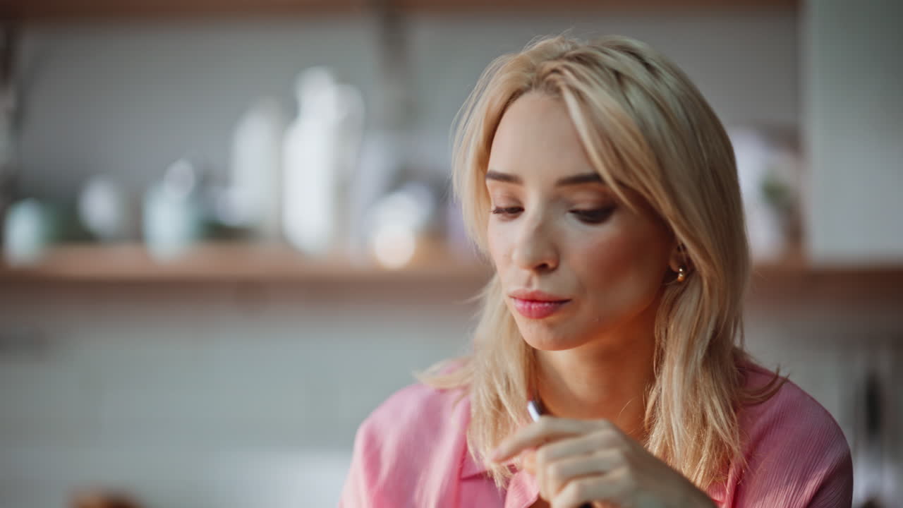 Thoughtful woman holding pen pondering at home portrait. Blonde taking coffee