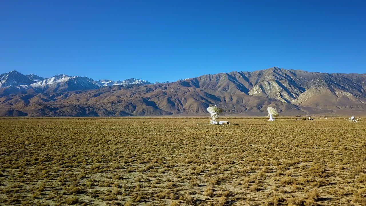 Aerial view towards space arrays and desert mountains - establishing, drone shot