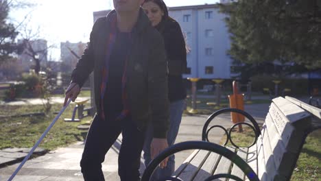 The-blind-man-and-his-wife-sit-on-a-bench-in-the-park.-They-are-a-happy-couple.