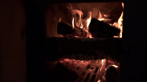 Closeup-shot-of-wood-burning-in-a-sauna-oven,-glass-door-opened-to-expose-the-flames