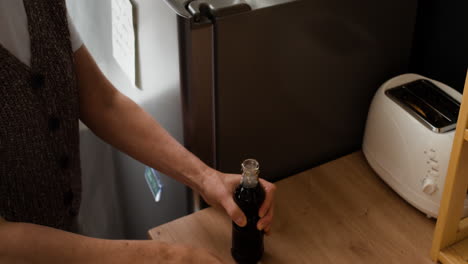 person opening a bottle with an opener in a kitchen