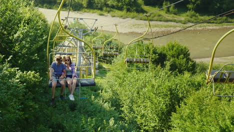 a happy young couple is riding on a ski lift photograph landscapes holidays in the mountains in summ