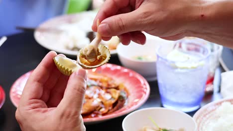 manos disfrutando de comida de almejas hervidas en un restaurante en phuket, tailandia