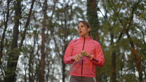 woman resting and rehydrating during a run in the forest