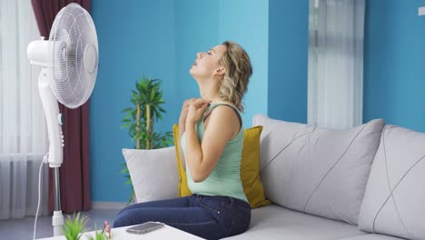 la mujer que usa el ventilador está abrumada por el calor.