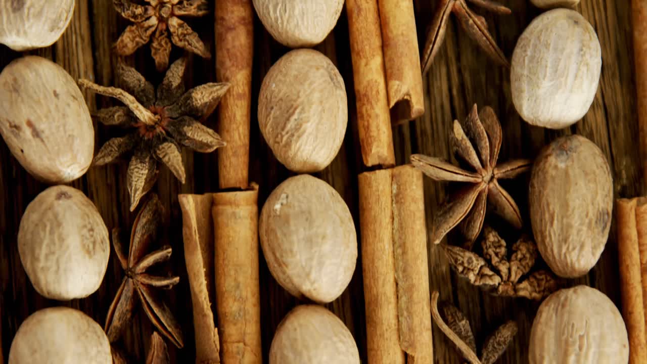 Nutmeg, star anise and cinnamon sticks arranged on wooden table 4k