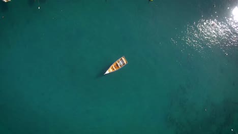 bird eye view of a small fishing boat floating in a calm caribbean sea marina