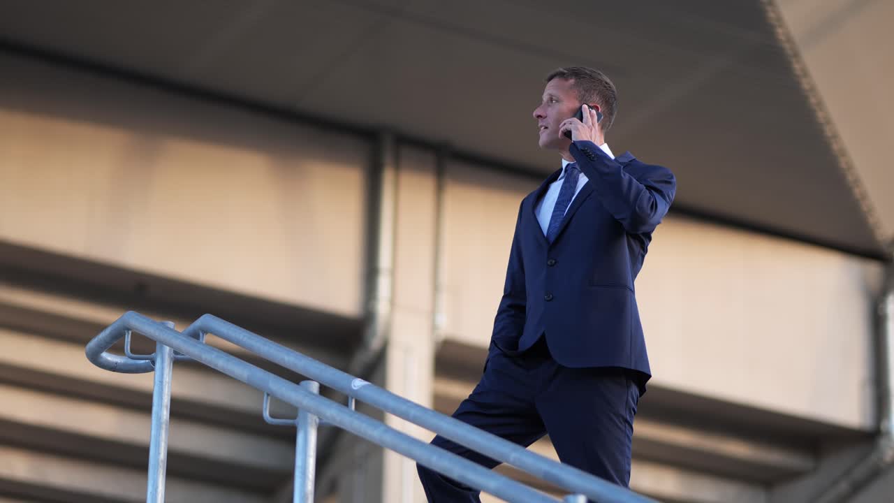 toma de órbita de un experimentado hombre de negocios caucásico de mediana edad bajo el techo de un edificio moderno en una llamada telefónica al aire libre