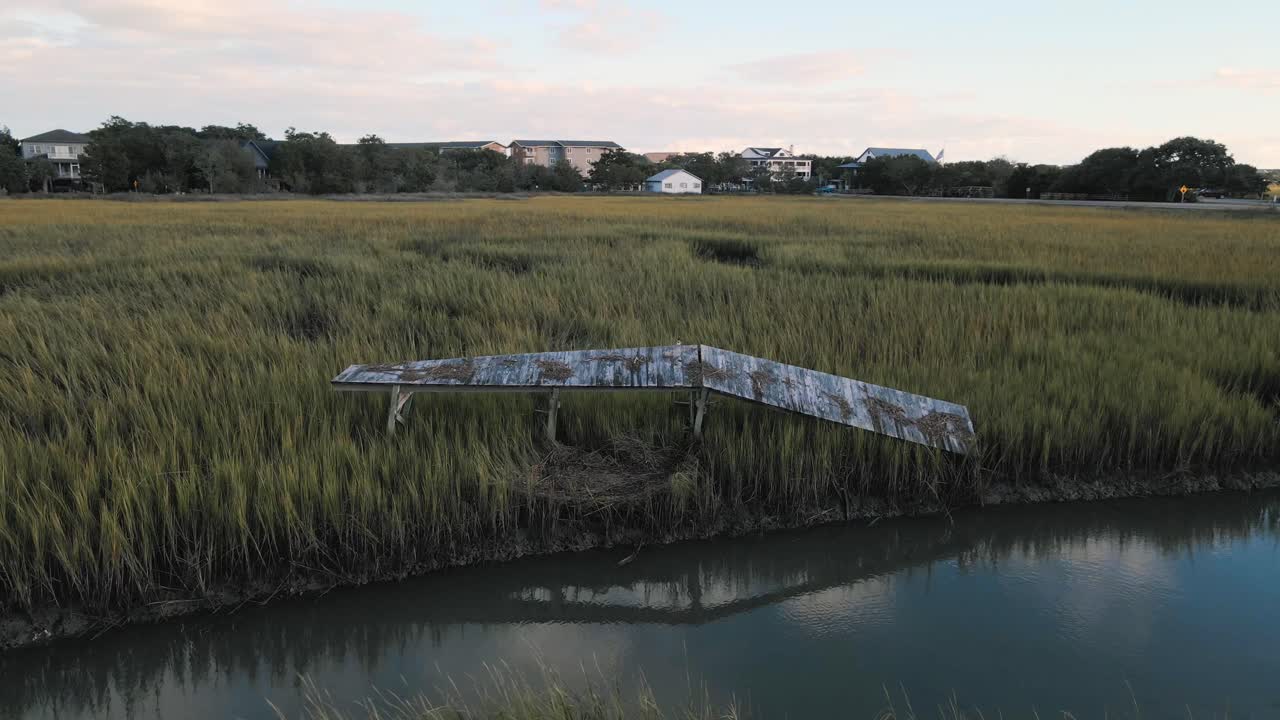 muelle abandonado y roto en la isla de pawleys después del huracán ian al atardecer con reflejo en el agua