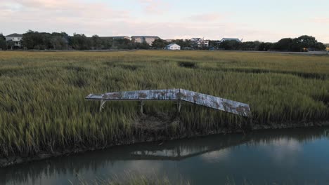 Verlassenes-Und-Kaputtes-Dock-In-Pawleys-Island-Nach-Dem-Hurrikan-Ian-Bei-Sonnenuntergang-Mit-Reflexion-Auf-Dem-Wasser