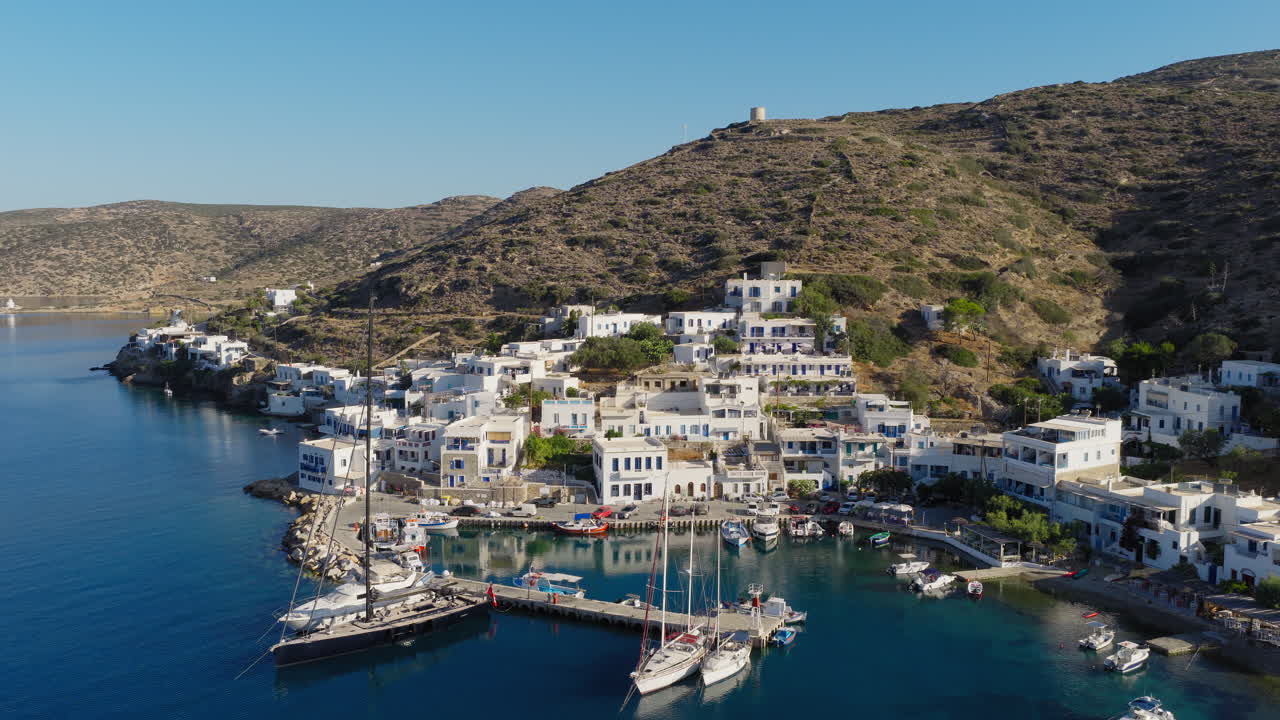 Katapola seaside village port with boats, houses and apartments on Amorgos island, Aerial pullback shot
