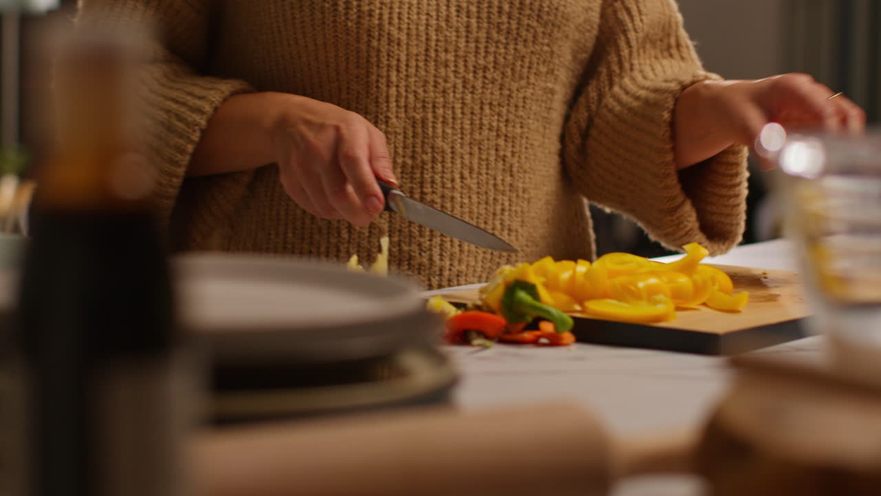 primer plano de una mujer en casa en la cocina preparando verduras frescas saludables para una comida vegetariana o vegana cortando pimientos rojos y amarillos a bordo