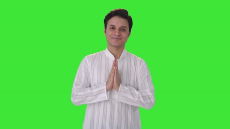 young indian man doing namaste green screen