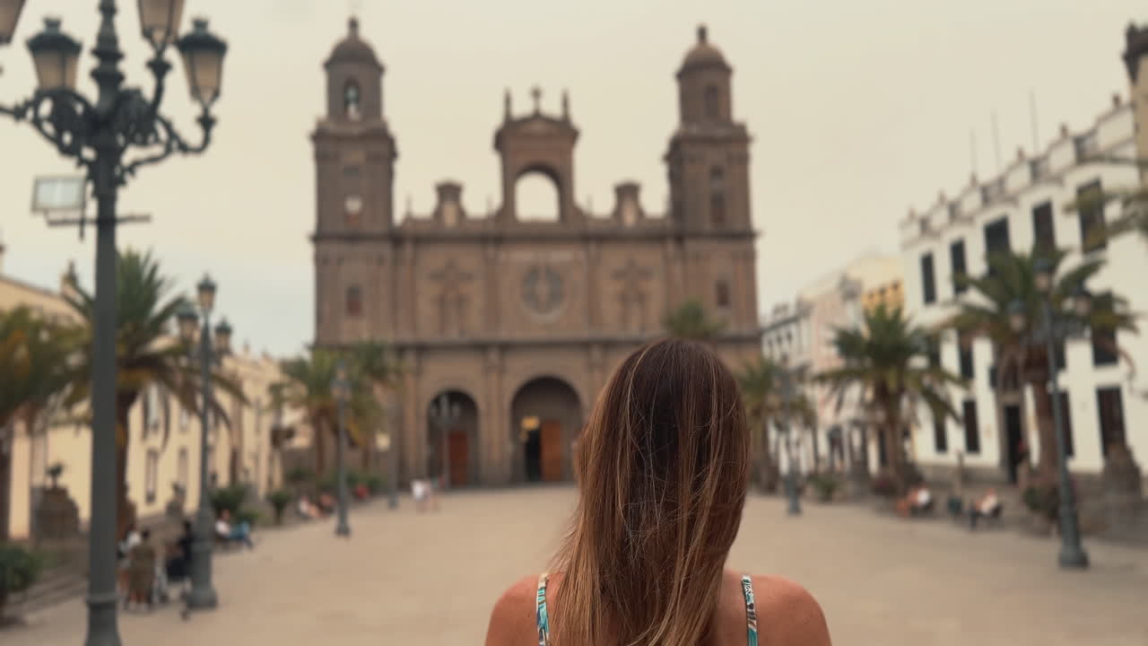 Tourist walking in Plaza de Santa Ana towards the main entrance of Las Palmas Cathedral in Gran Canaria