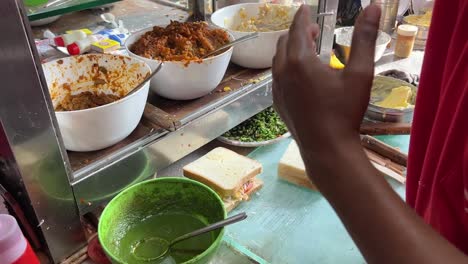 closeup shot of indian styled sandwiches getting sliced into halves at a roadside stall in kolkata, india