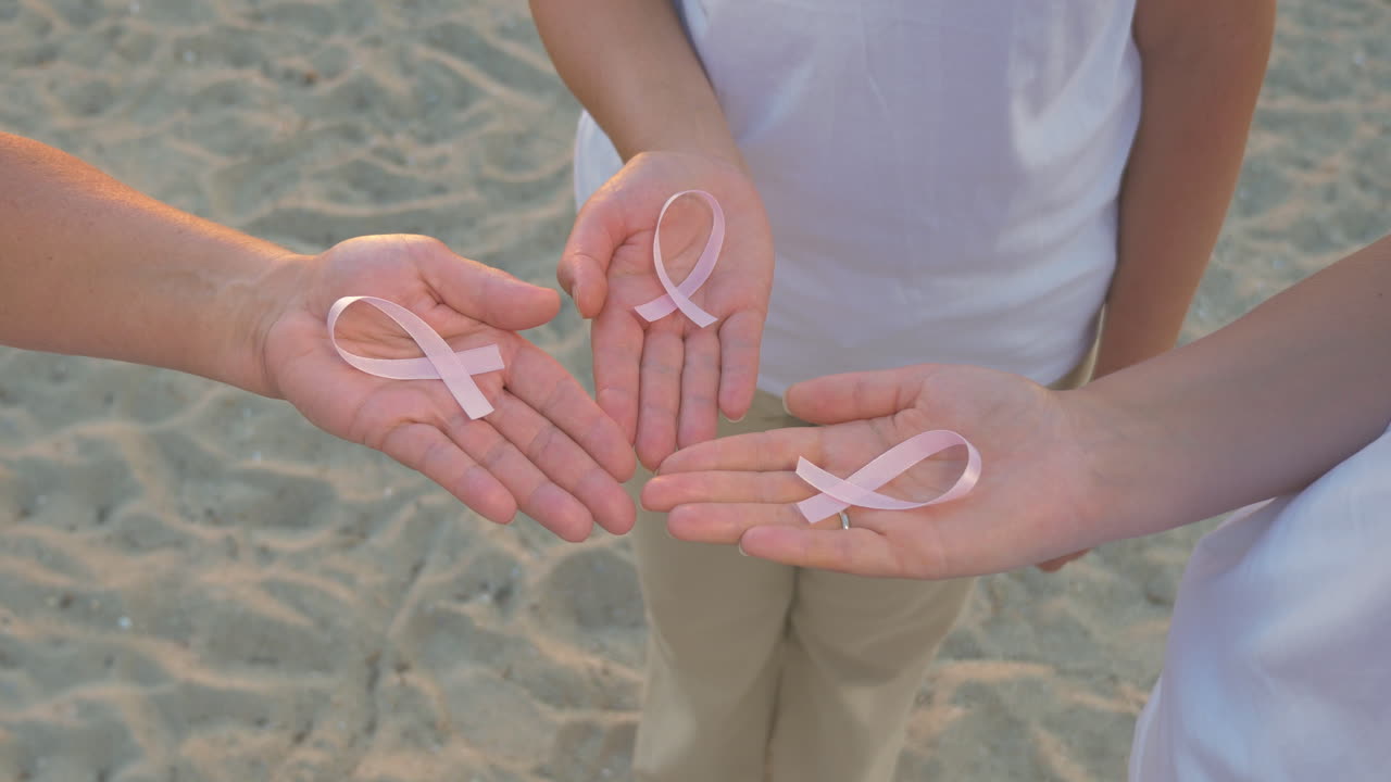 Tre mani che tengono un nastro per la consapevolezza del cancro