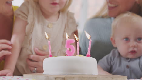 grandparents with mother at party singing happy birthday to granddaughter on fifth  birthday at home