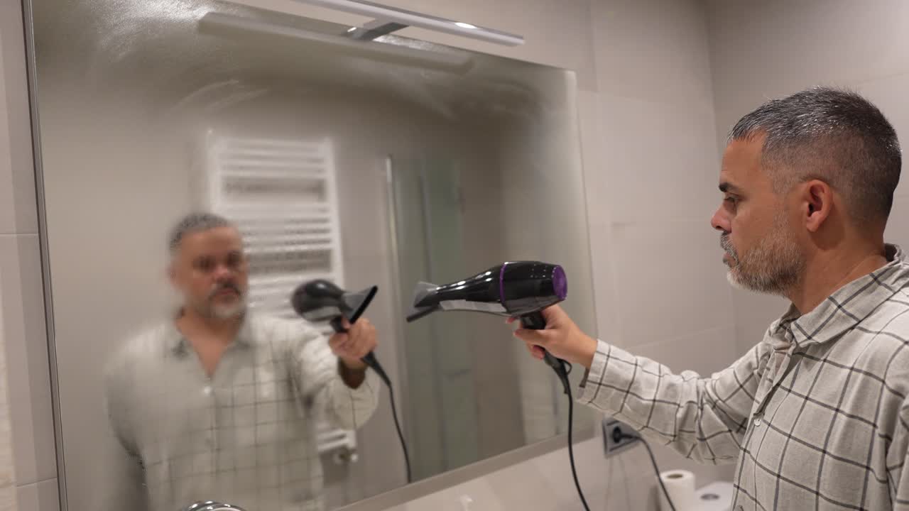 Désembuage d’un miroir avec un sèche-cheveux dans la salle de bain
