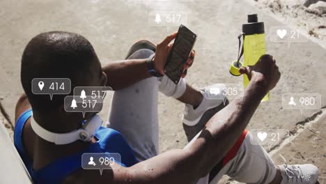 animation of notification icons over exercising african american man taking a break using smartphone