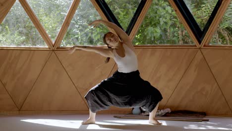 mindful yoga session with a latina woman practicing in a tranquil geometric studio crouching and bending side to side to stretch